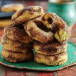 Cinnamon baked donuts stacked on a green plate with brown sugar cinnamon filling visible inside