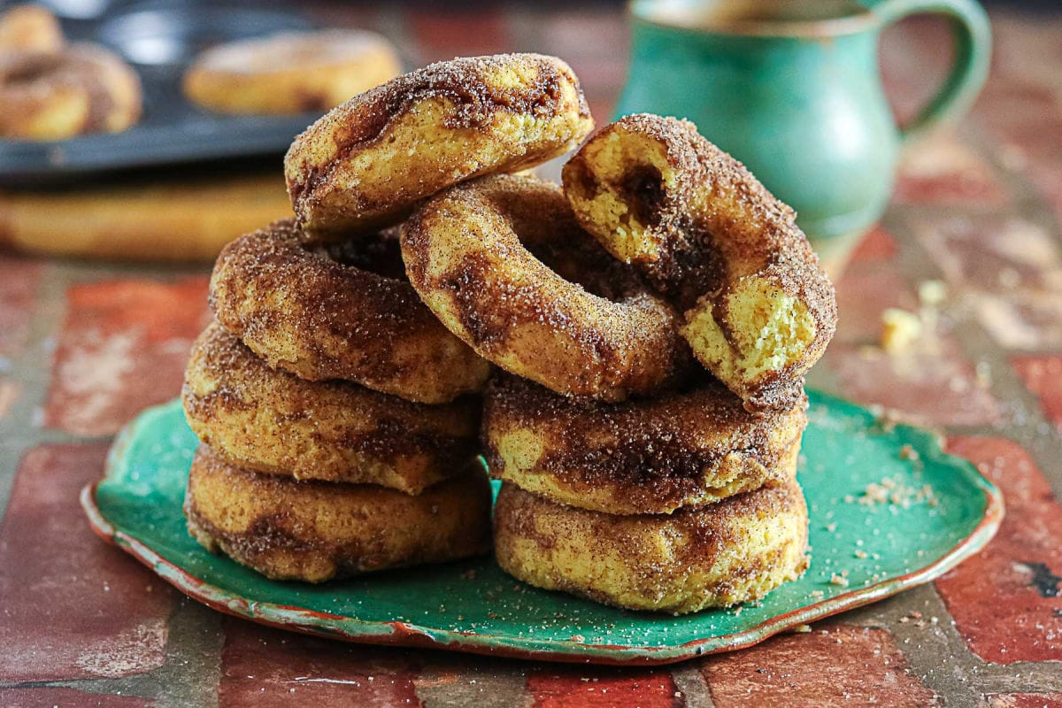 Cinnamon baked donuts stacked on a green plate with brown sugar cinnamon filling visible inside