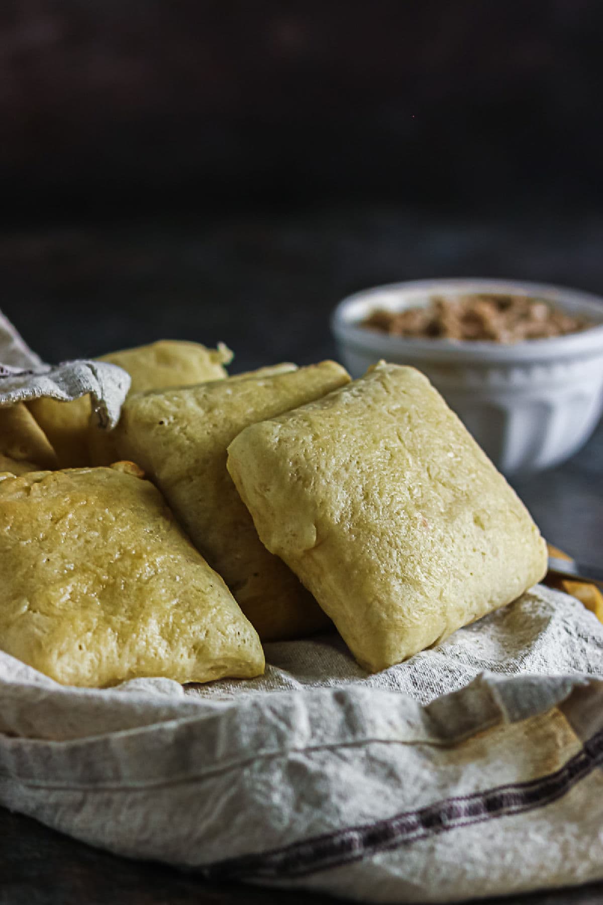 Copycat Texas Roadhouse rolls piled on a linen napkin with cinnamon honey butter in the background