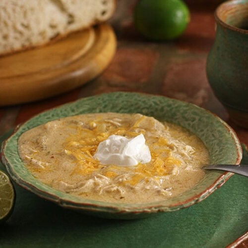 Creamy green enchilada chicken soup topped with shredded cheese and sour cream