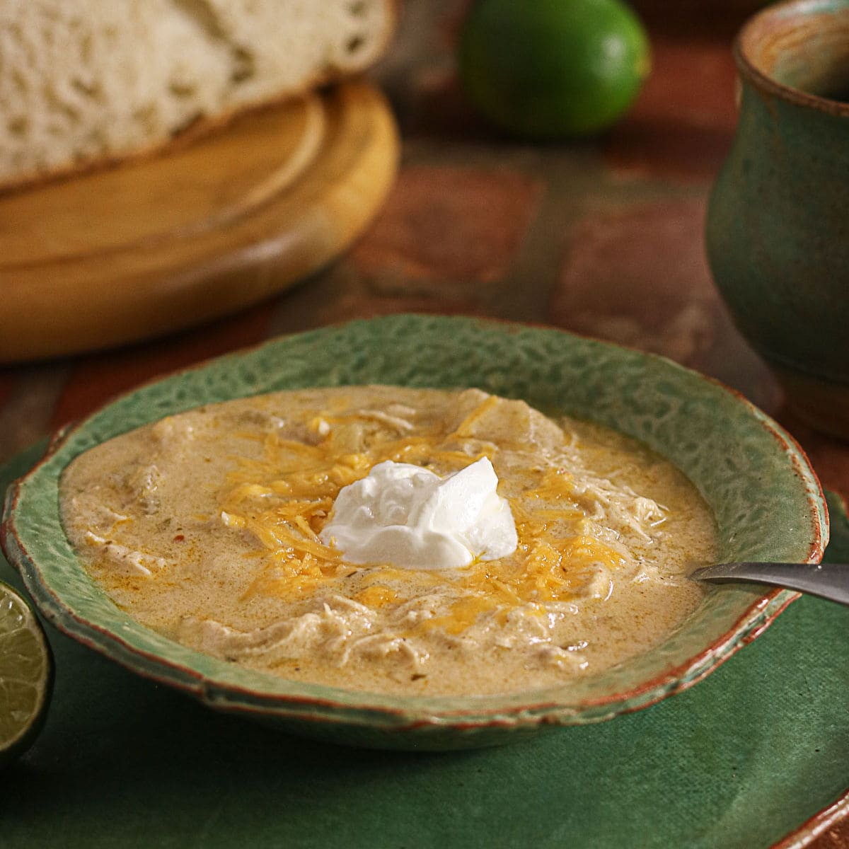 Creamy green enchilada chicken soup topped with shredded cheese and sour cream