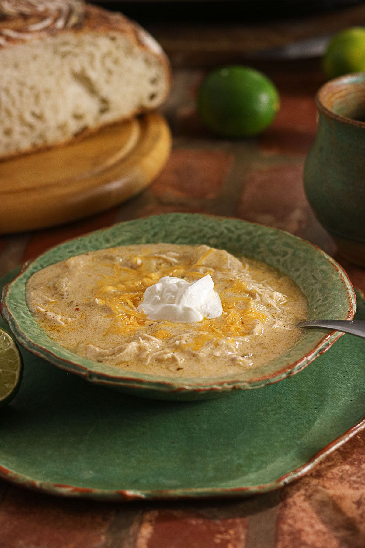 Creamy green enchilada chicken soup topped with shredded cheese and sour cream