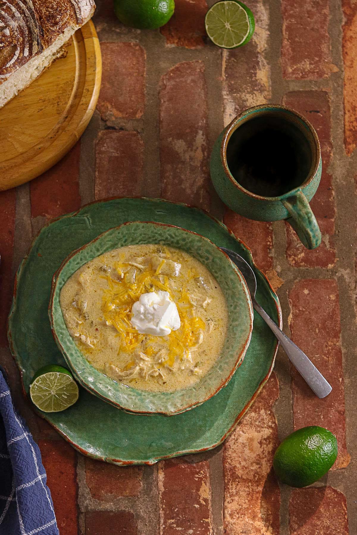 Crockpot green enchilada chicken soup served with lime and crusty bread.
