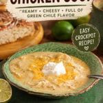 Creamy green enchilada chicken soup topped with shredded cheese and sour cream with lime and bread.