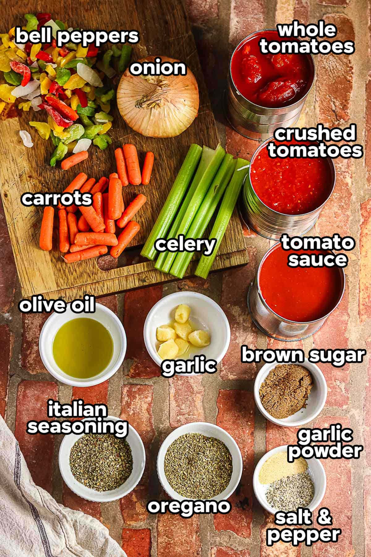 Ingredients for slow cooker spaghetti sauce including tomatoes, peppers, onion, carrots, celery, and seasonings