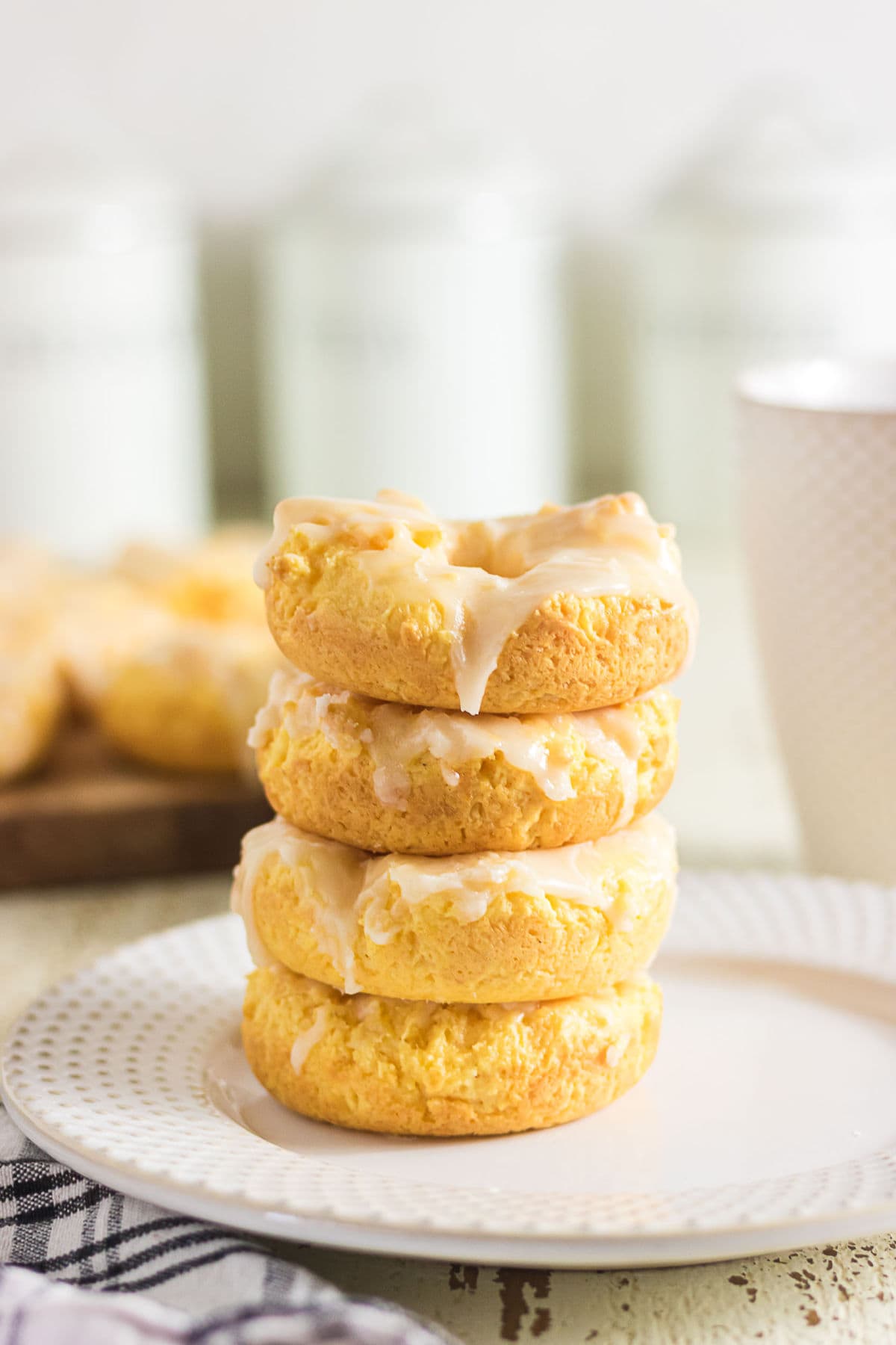 Stack of four golden sour cream baked donuts topped with a simple vanilla glaze.