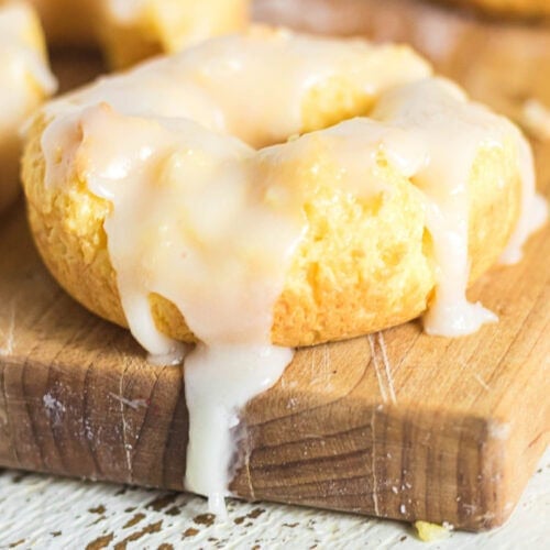 Close-up of a sour cream baked donut with thick vanilla glaze dripping over the sides.