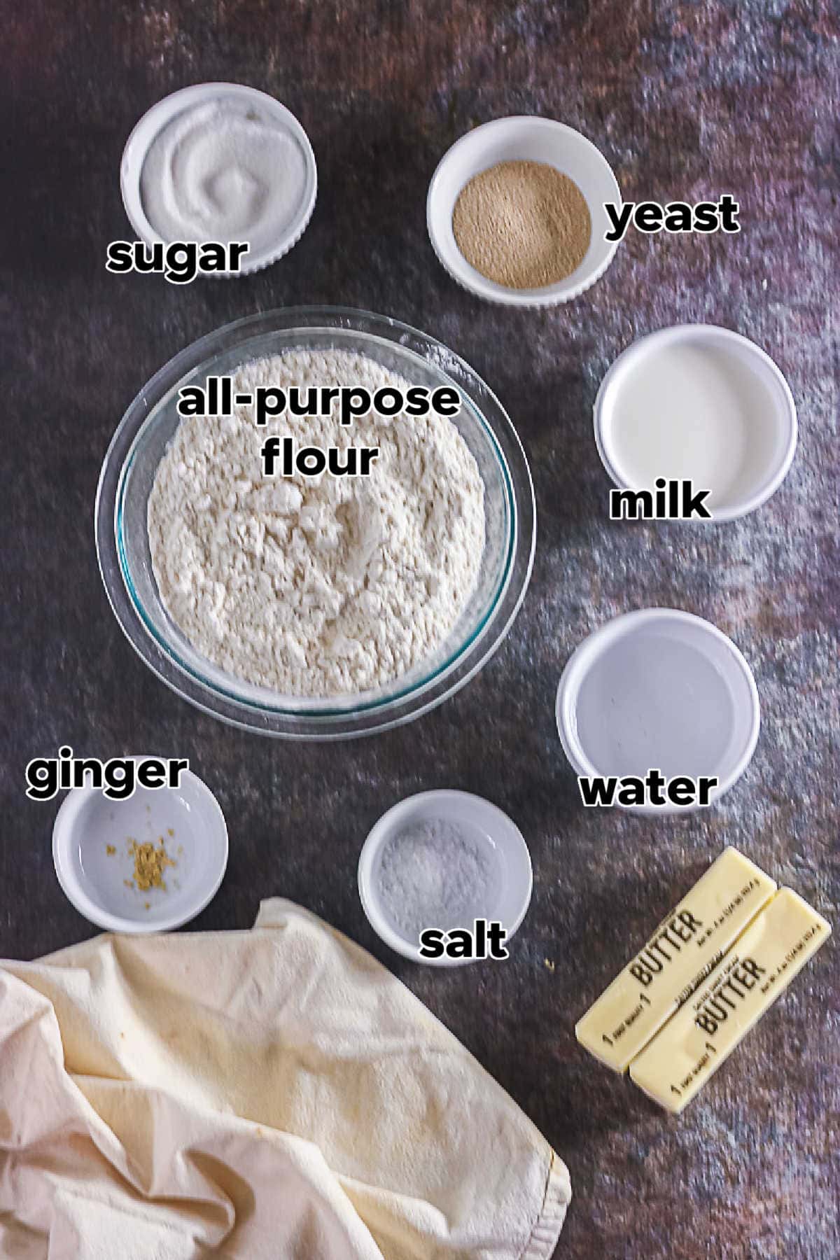 Ingredients for homemade Texas Roadhouse rolls including flour, milk, yeast, sugar, butter, water, salt, and ginger