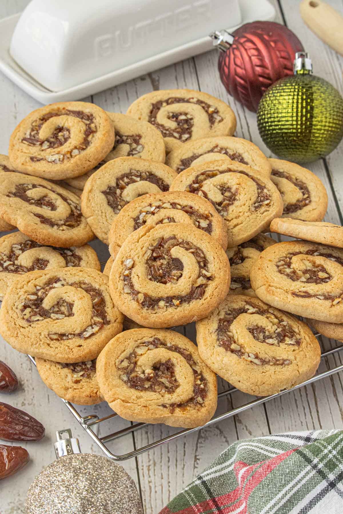 Homemade date nut pinwheel cookies with swirls of date and pecan filling cooling on a wire rack with Christmas decorations