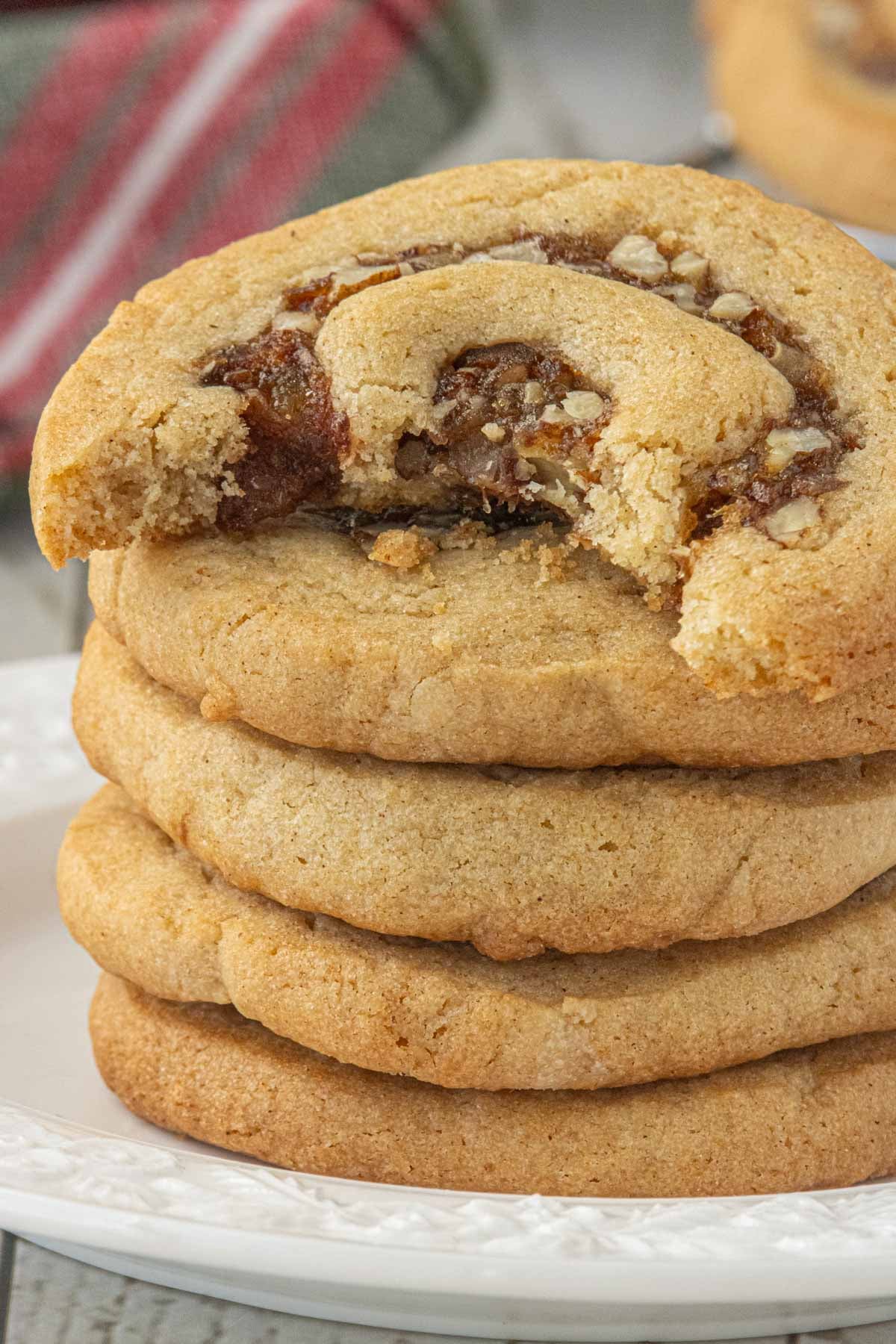 Stack of soft date nut pinwheel cookies with a bite taken from the top cookie, revealing the date and pecan filling.