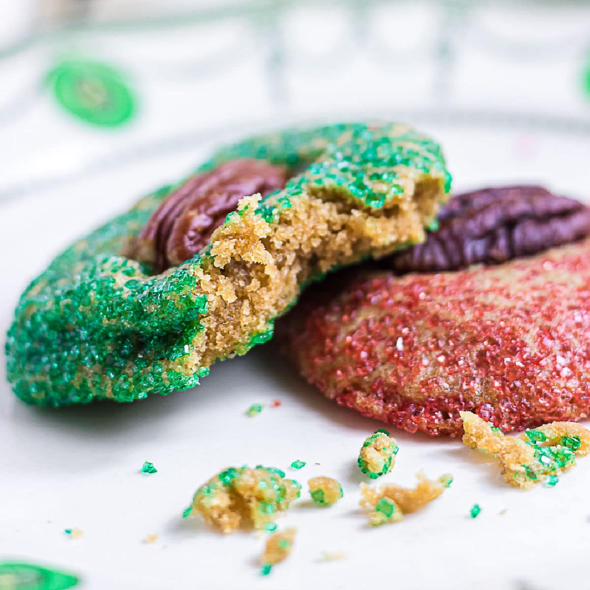 Close-up of a broken brown sugar butter cookie showing its tender golden center, crisp edges, and green sparkling sugar coating.