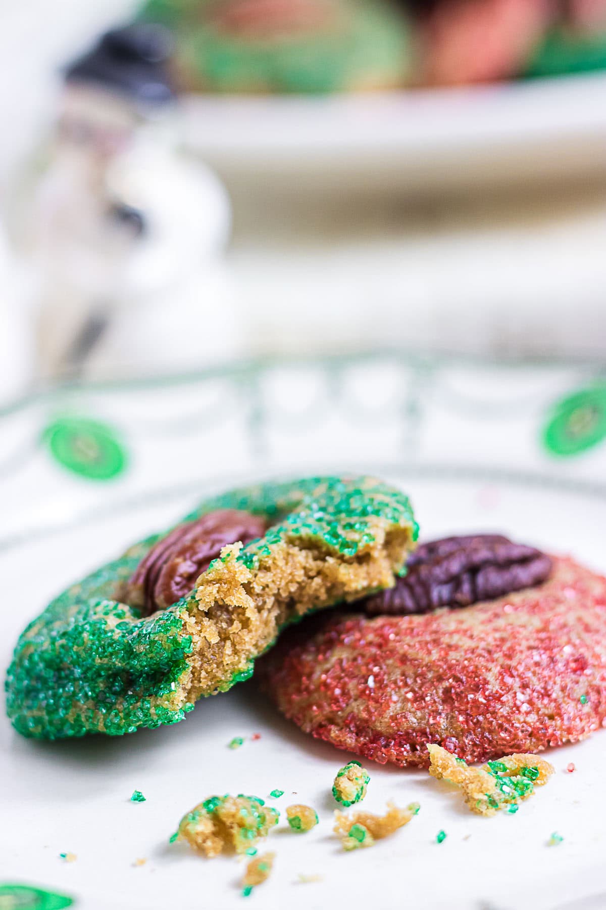 Broken Christmas butter cookie revealing a tender brown sugar center with a crisp, sugar-coated edge and pecan-topped cookies behind it.