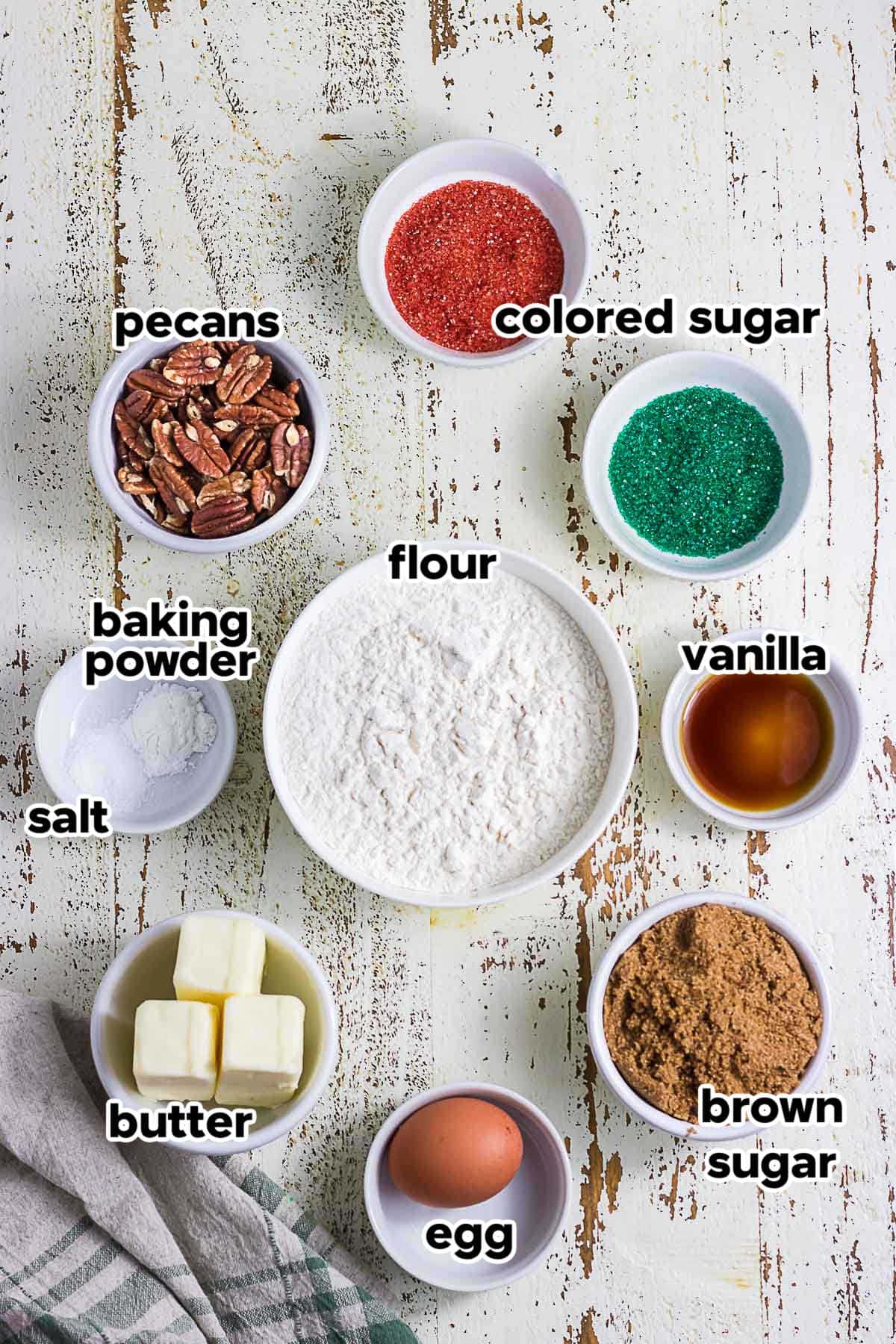 Ingredients for old-fashioned butter cookies, including butter, brown sugar, flour, egg, vanilla, pecans, and red and green decorating sugar.