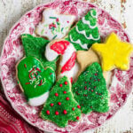 Decorated Christmas cutout sugar cookies with green Christmas trees, a yellow star, and red and white candy cane icing.