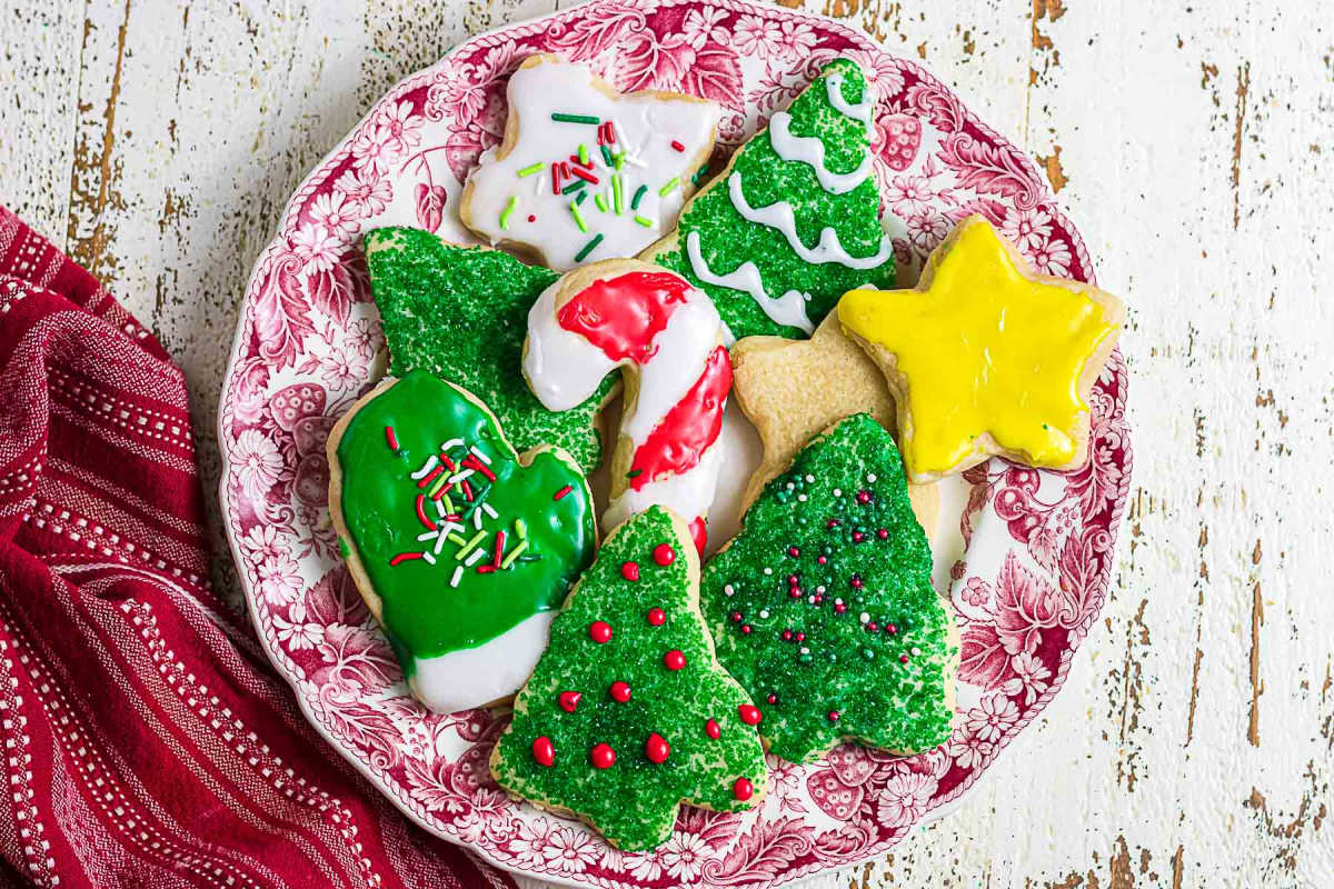 Decorated Christmas cutout sugar cookies with green Christmas trees, a yellow star, and red and white candy cane icing.