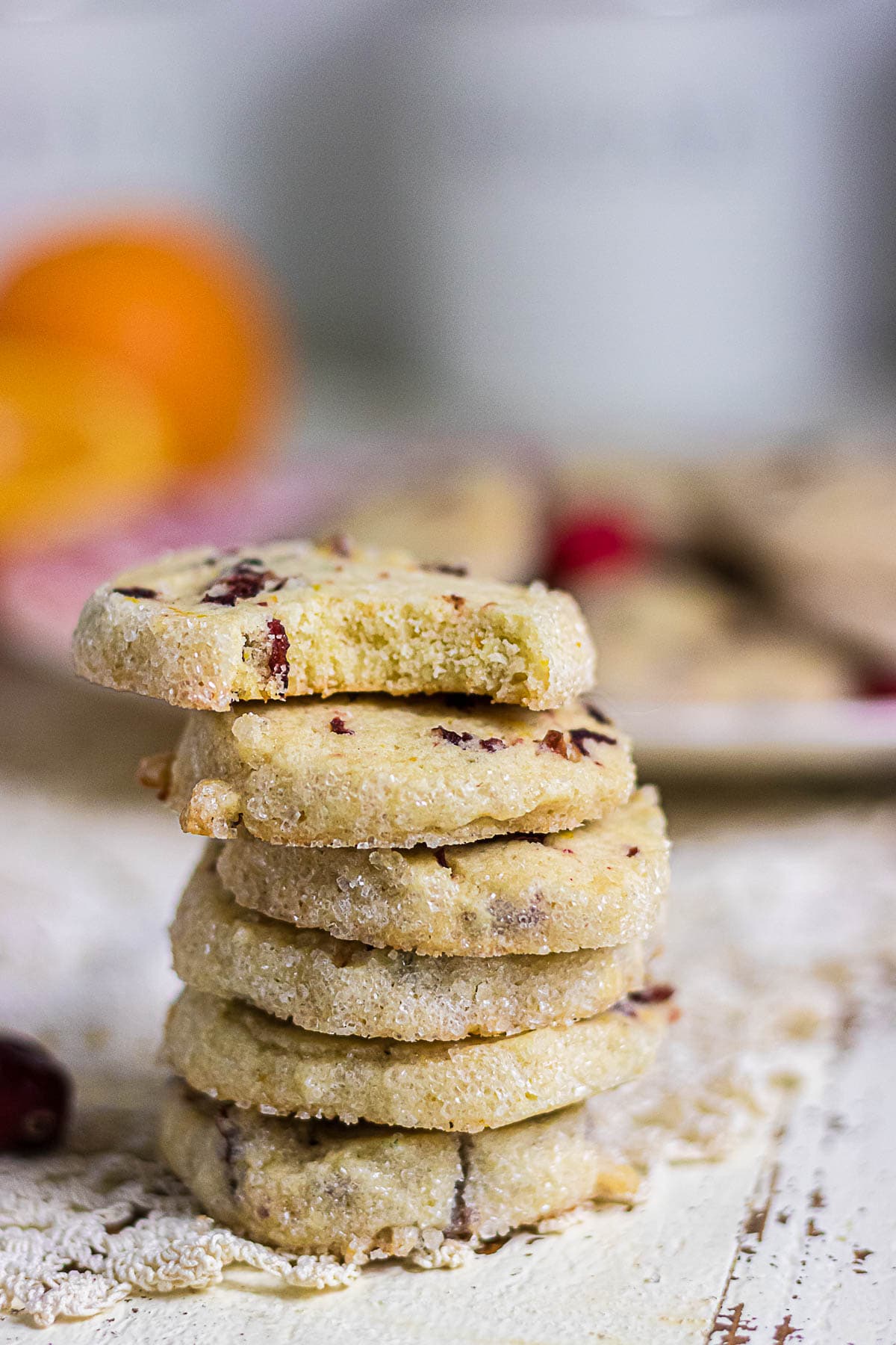 Stack of buttery cranberry orange icebox cookies showing their tender centers, golden edges, and sparkling sugar coating.