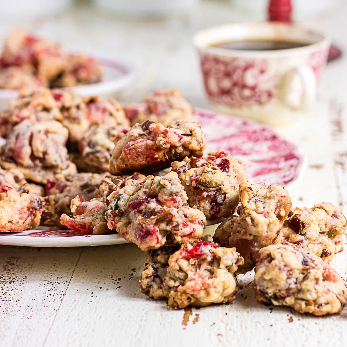 Chunky fruitcake cookies filled with colorful candied fruit and chopped pecans, served on vintage red and white china.