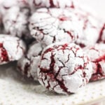 Red velvet crinkle cookies coated in powdered sugar on a white plate