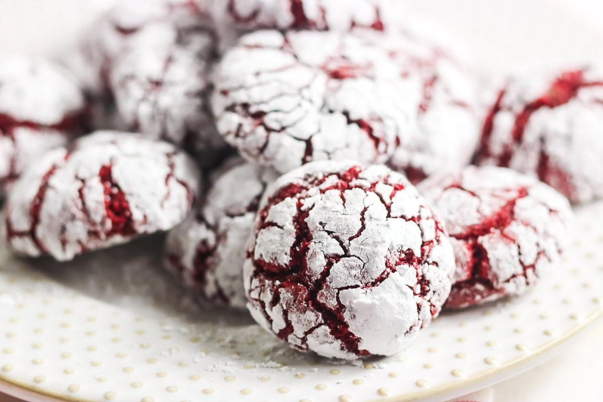 Red velvet crinkle cookies coated in powdered sugar on a white plate