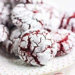 Close-up of a red velvet crinkle cookie with powdered sugar and deep red cracks