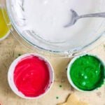 Homemade sugar cookie glaze in white, yellow, red, and green with piping bags.