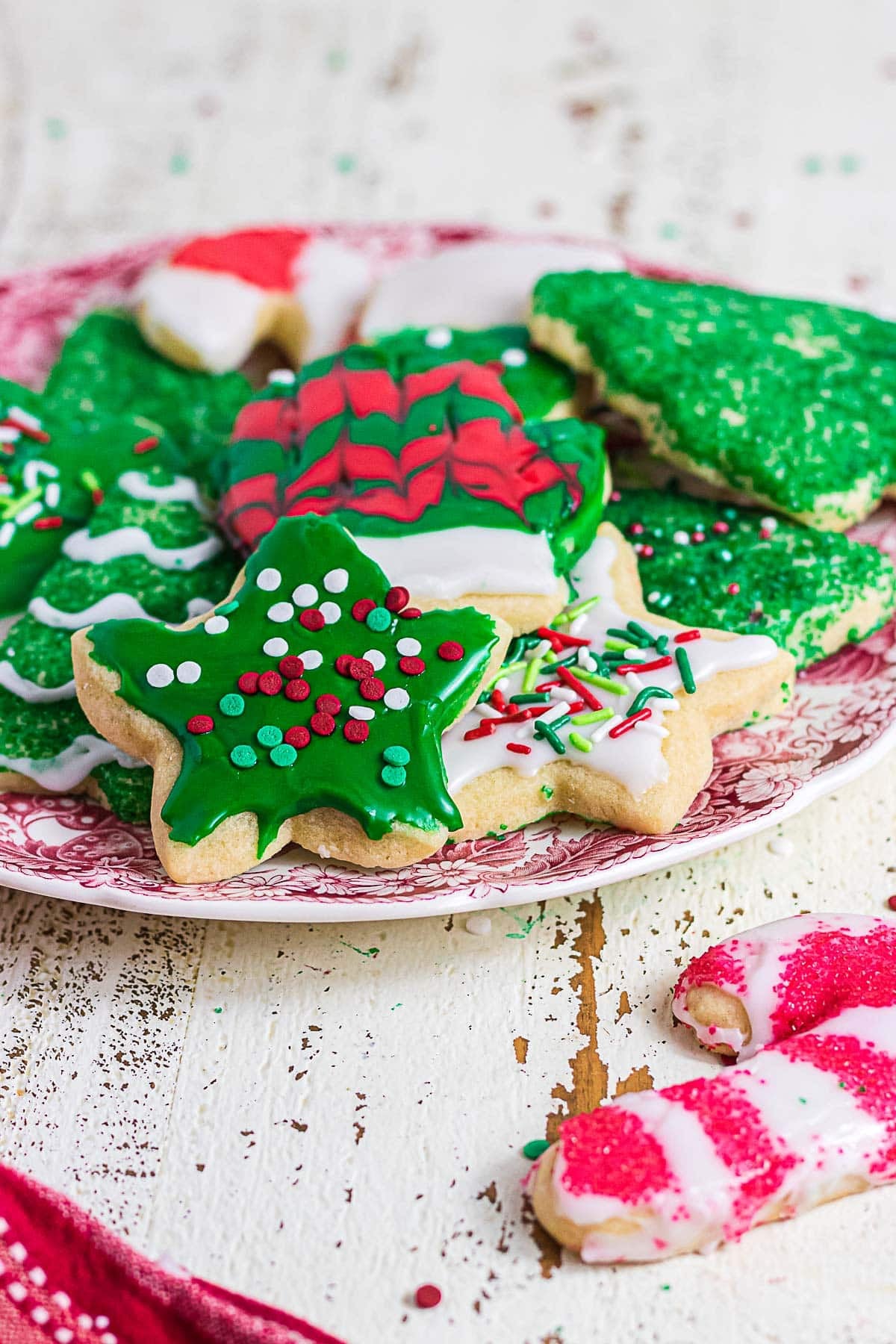 Decorated Christmas sugar cookies with colorful glaze and sprinkles arranged on a vintage red and white plate